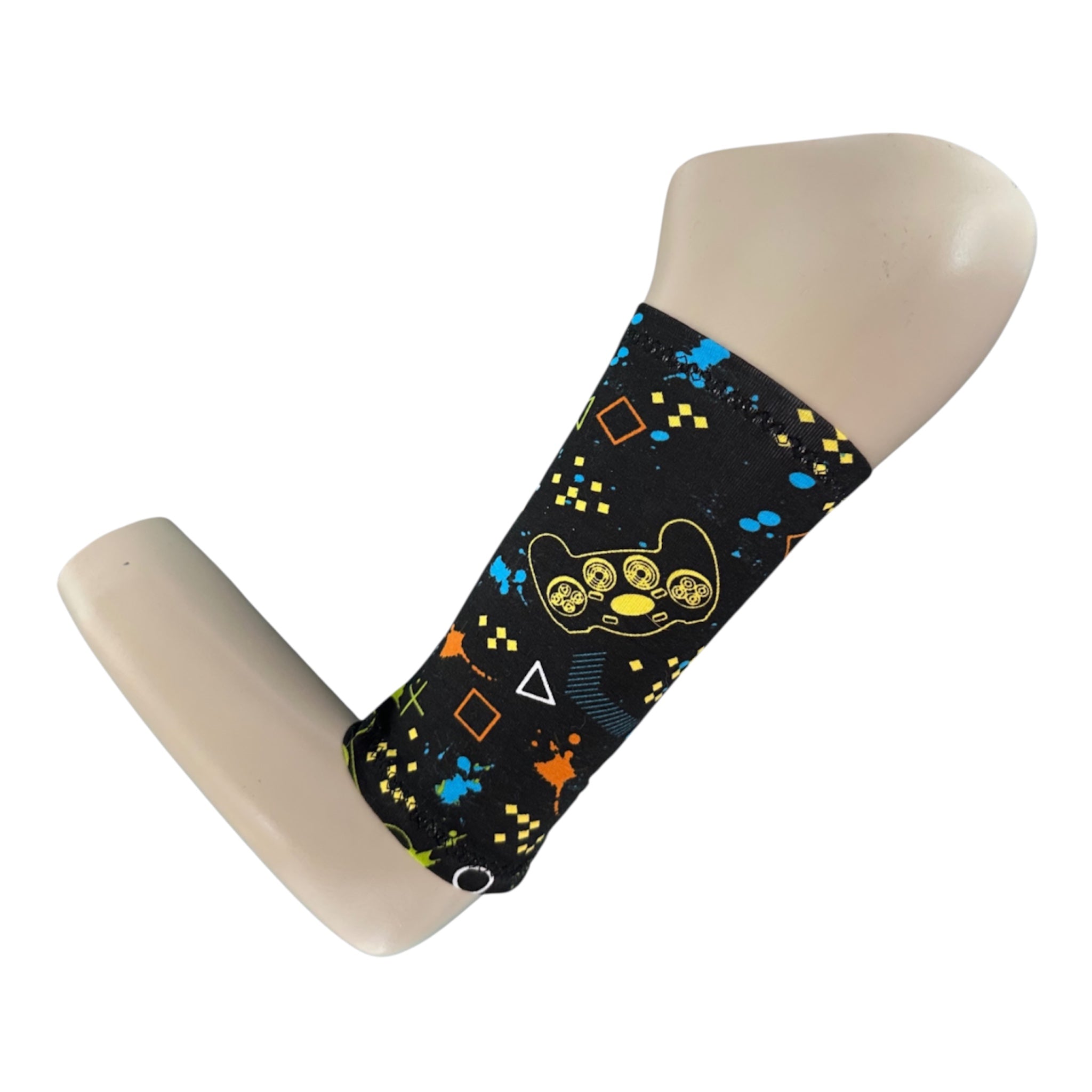 A black picc line cover with a gamer controller and gaming symbols print. rint is in blue, orange, yellow and green. Armband is displayed on a manequinn arm.