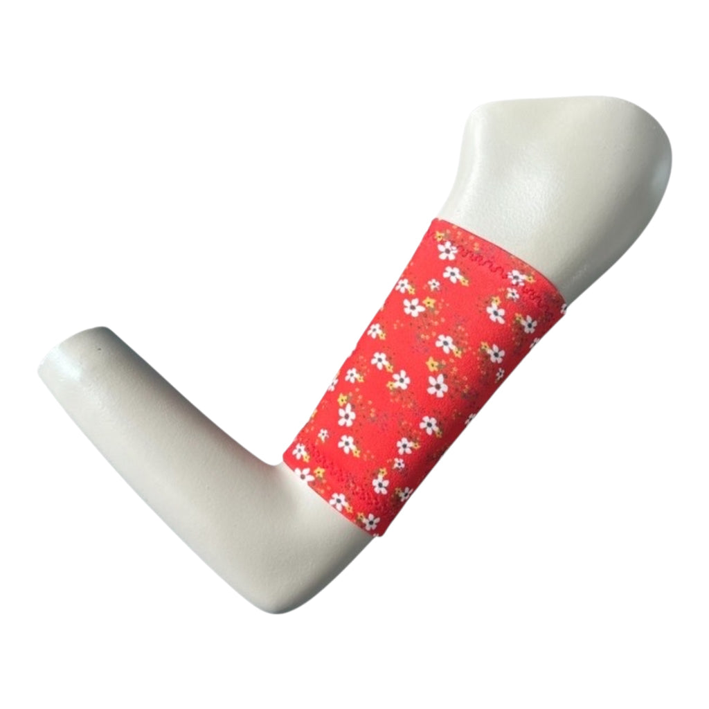 Red picc line armband cover sleeve displayed on a mannequinn arm. The cover has a ditsy small flower print in wjite and yellow.
