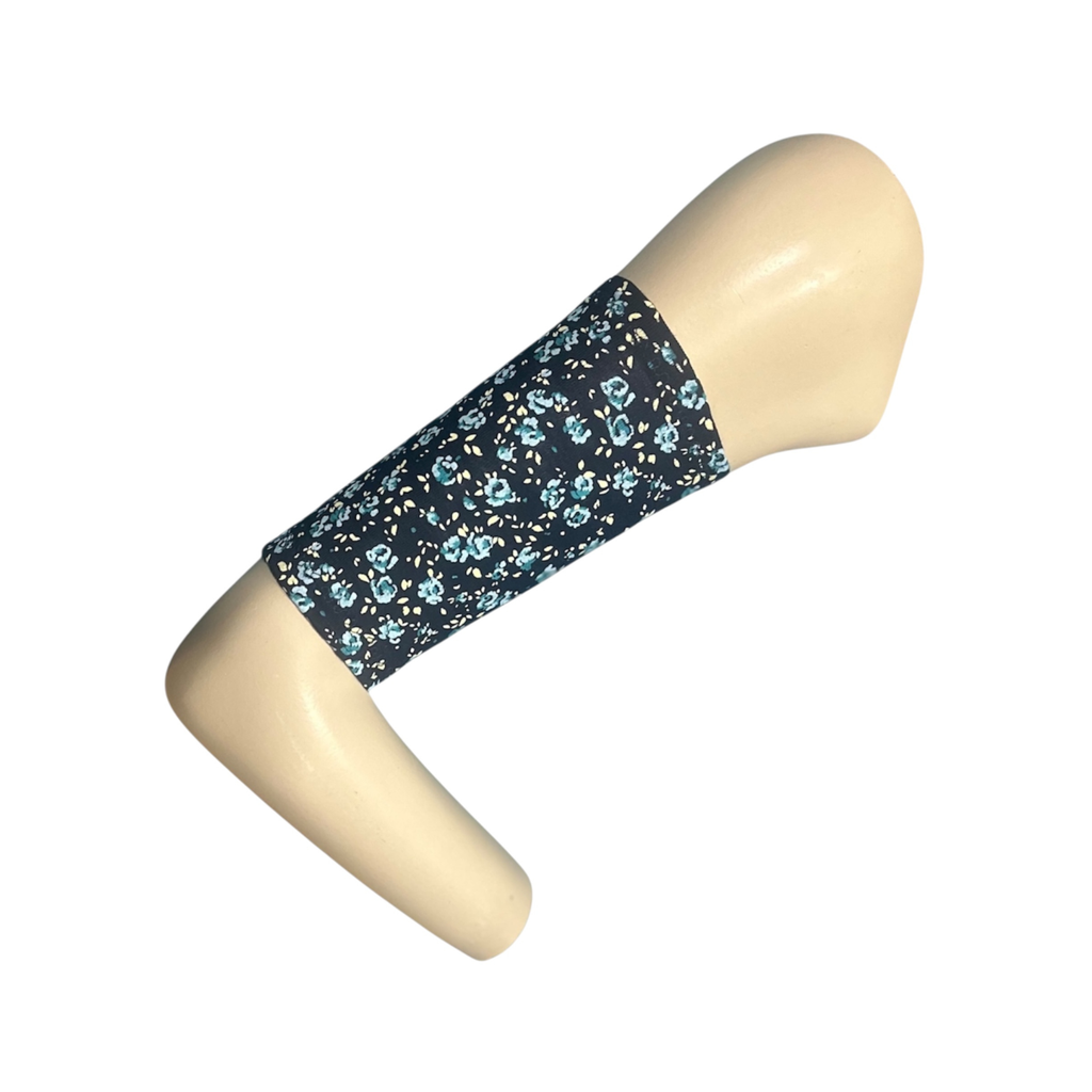 A navy blue picc line cover with a pale blue ose floral print. Armband is displayed on a manquinn arm